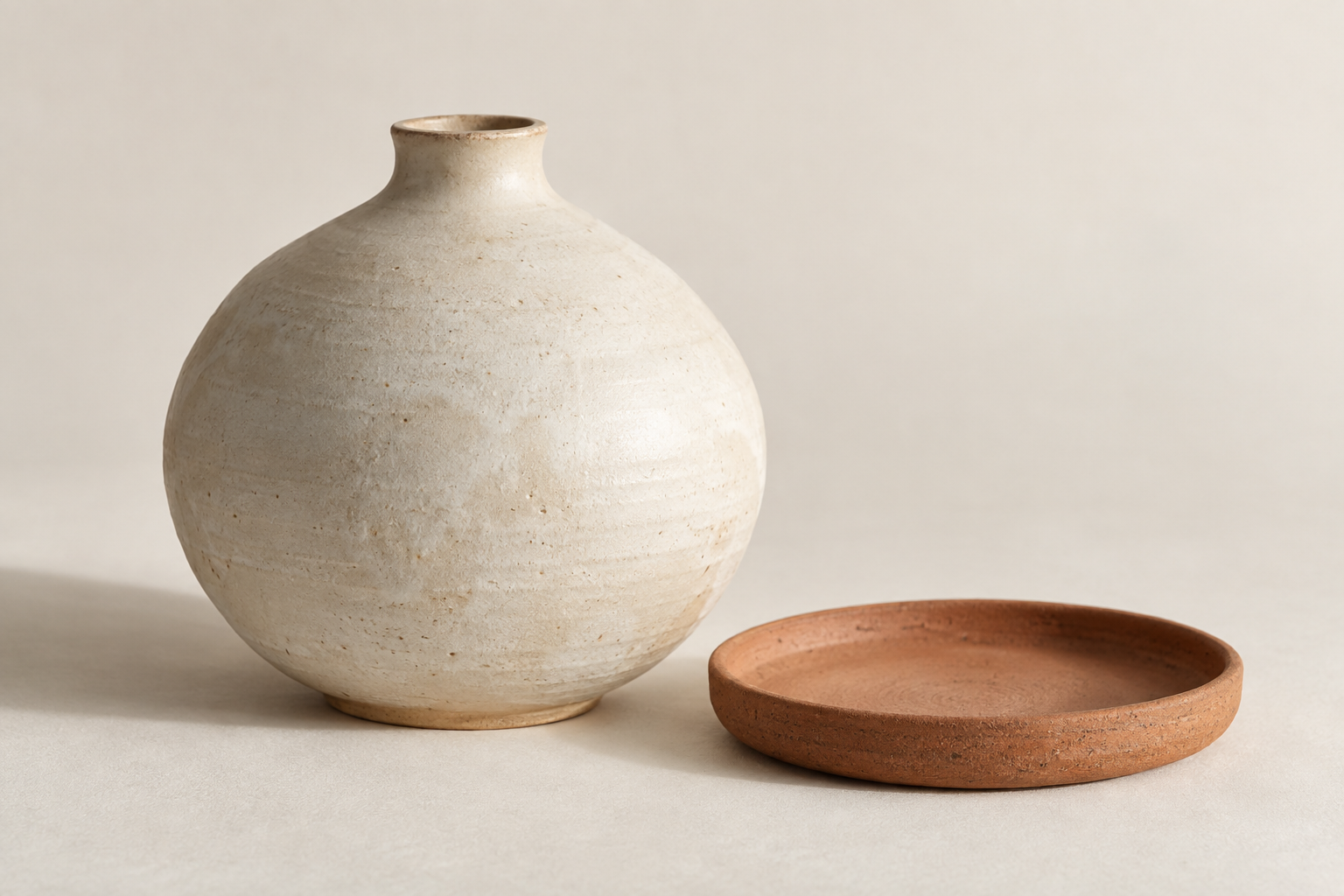 A ceramic vessel beside a clay tray